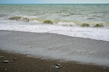 Sea shore with pebbles, wet sea pebbles on the beach and quiet sea surf