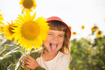 funny little child girl with a sunflower in a field with sunflowers. Slow life. Enjoying the little things. 