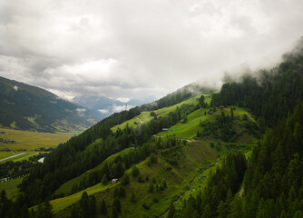 Fototapeta premium A hill covered in mist during summer, creating a serene and mysterious atmosphere. The fog blankets the landscape, adding a soft, ethereal touch to the green surroundings.