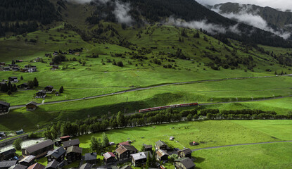 Spring day in mountain valley. Small town with farm fields and railway passing trough. Green...