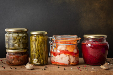 Preserving vegetables for the winter, canned vegetables in jars on a wooden table against a brown wall, pickled or fermented vegetables, copy space