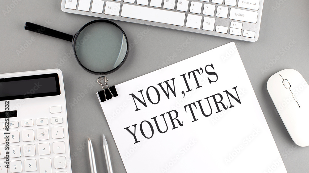 Fototapete now it's your turn written on paper with office tools and keyboard on the grey background