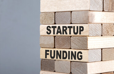 The text on the wooden blocks STARTUP FUNDING