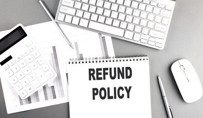 REFUND POLICY text written on notebook on grey background with chart and keyboard, business concept