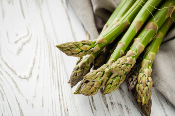 raw green asparagus on a white rustic wooden background