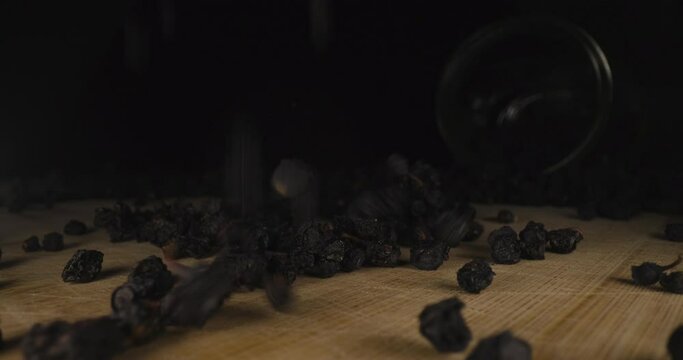 Dried European blueberry Vaccinium myrtillus falling on wooden table, close up of bilberry fresh organic dehydrated fruit