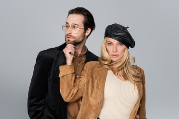 blonde woman in stylish beret near bearded man in sunglasses isolated on grey