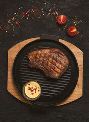 pork steak with vegetables in a black iron pan , top view.