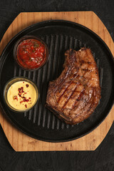 pork steak with vegetables in a black iron pan , top view.
