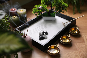 Beautiful miniature zen garden, incense sticks and oil lamps on table