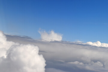 Dramatic sky with the landscape of white clouds viewed from a high altitude. Viewed from an airplane window.