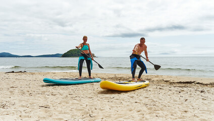 A man SUP board instructor on the shore teaches a girl how to stay on the water. Active rest on the sea.