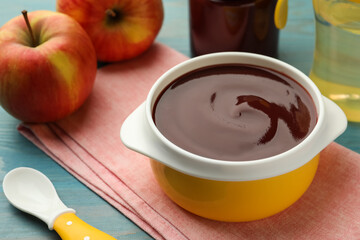 Bowl with tasty pureed baby food and ingredients on light blue wooden table