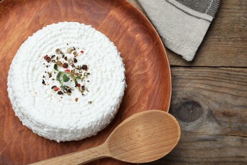 Fototapeta na wymiar Wooden plate of fresh cottage cheese with spice and microgreens on table, top view
