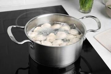 Cooking delicious dumplings in pot on cooktop