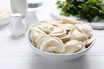 Fototapeta na wymiar Delicious dumplings in bowl on white wooden table