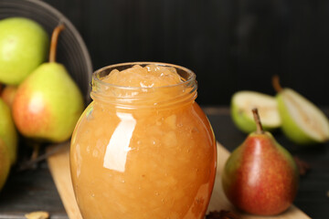 Delicious pear jam in glass jar on table, closeup