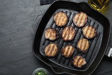 Delicious grilled eggplant slices in pan on black table, flat lay. Space for text