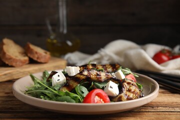 Delicious salad with roasted eggplant, feta cheese and arugula served on wooden table