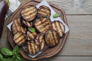Delicious grilled eggplant slices served on wooden table, flat lay