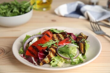 Delicious salad with roasted eggplant and arugula served on wooden table