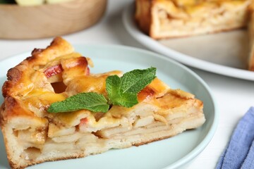 Slice of traditional apple pie with mint on plate, closeup