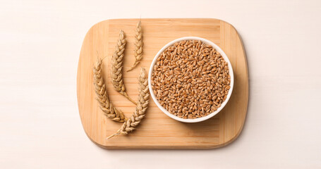 Wheat grains with spikelets on white table, top view
