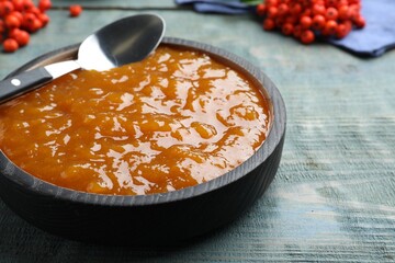 Delicious rowan jam in bowl on light blue wooden table, closeup