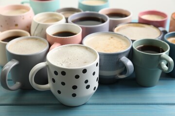 Many cups of different coffee drinks on light blue wooden table