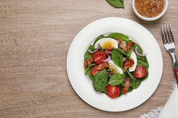 Delicious salad with boiled egg, bacon and vegetables served on wooden table, flat lay. Space for text