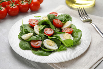 Delicious salad with boiled eggs, tomatoes and spinach on light grey table, closeup