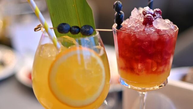 Orange and red cocktails, lemonade and vodca, mango juice, blueberries and ice