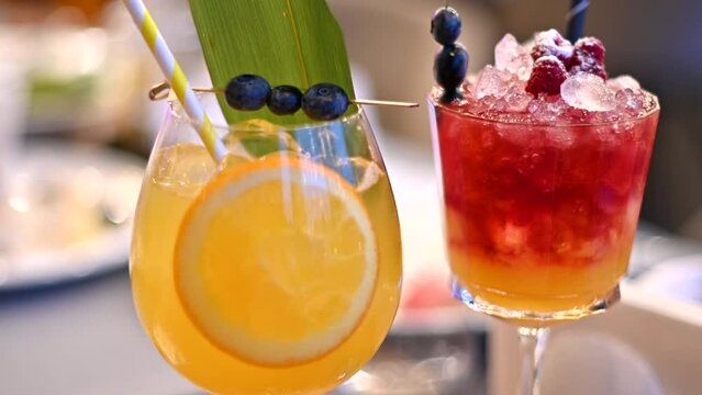 Orange and red cocktails, lemonade and vodca, mango juice, blueberries and ice