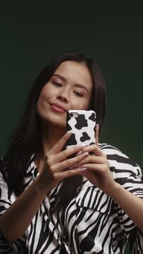 A young asian woman on a green background is taking a selfie