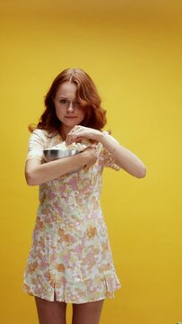 A young white ginger woman on a yellow background being emotional and eating popcorn, watching a movie