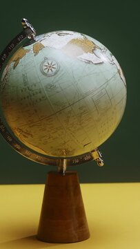 A spinning globe on a yellow table, a finger pointing at destinations on a green background