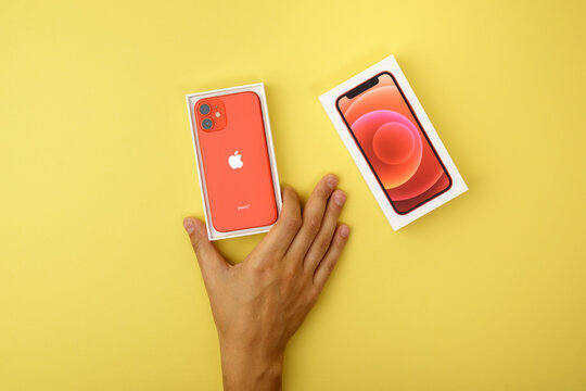 Tyumen, Russia-July 18, 2022: iPhone 12 mini Product red with retail box. Top view, yellow background