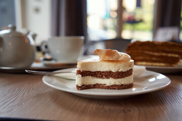Cream cake on a table in a cafe, with a teapot in the background