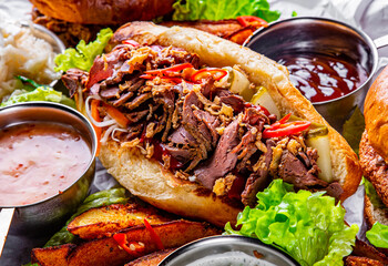 Philly cheese steak sandwich with meat, vegetables, cheese and sause on wooden table. street food