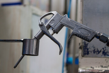 An aluminum air pistol grip rests on a stainless steel perforated cylinder.