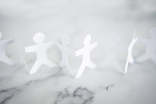 manpower and teamwork, paper people chain with text on white marble background