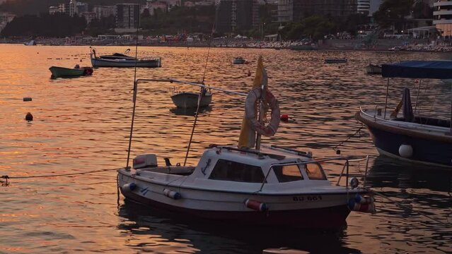 old fish boats in the sea against the backdrop of a beautiful orange sunset setting the mountains. A magnificent landscape of sea boats against the backdrop of the sunset. Beautiful sunset.