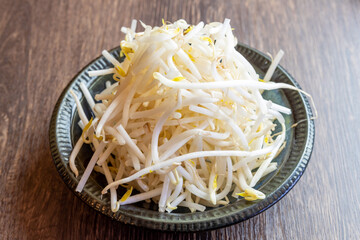 新鮮でシャキシャキとした食感が魅力の「生もやし」。一皿にたっぷりと盛り付けられたシンプルな素材は、料理のトッピング、ナムルや炒め物のレシピ紹介、節約料理のイメージカットに最適な高品質フード素材です。 | Fresh raw bean sprouts piled on a plate.
