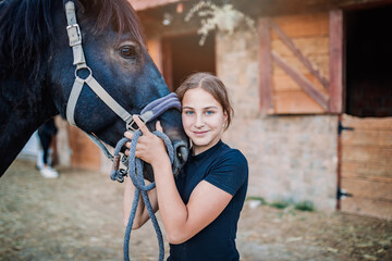 Beautiful girl embracing her horse and smiling outdoors at ranch.