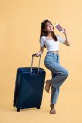 Young attractive Asian woman traveler wearing sunglasses standing with luggage, passport and boarding pass ticket isolated on yellow background, Tourist girl having cheerful holiday trip concept