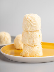 Creative concept sweet cotton candy pashmak stands in a pyramid on top of each other. Pastel beige background