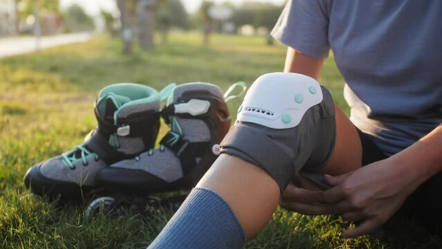 Woman putting on knee pads before training. Active outdoor sport. Close-up legs.