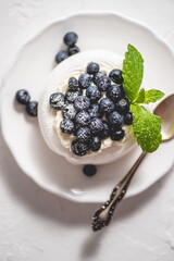 Delicious mini Pavlova meringue nest with blueberry and mint leaves