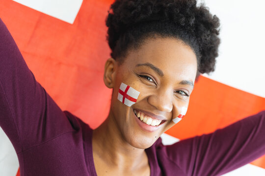 Image of happy african american woman with flags of england on face over flag of england