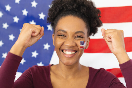 Image of happy african american woman with flags of usa on face over flag of usa